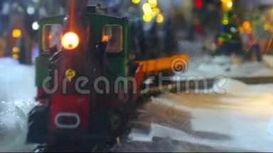 圣诞玩具火车模型雪地上的特写轨道，背景是乡村灯光